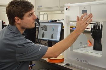 Engineer using a CubeX Trio 3D printer to prototype a protective glove, demonstrating Codespa Divitex product development capability